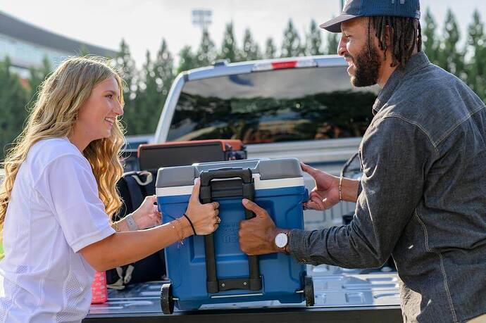 Couple unloading cooler from truck for tailgate party