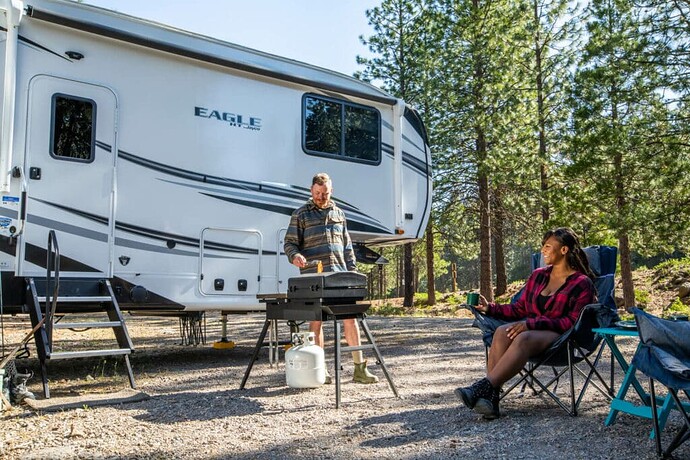 Couple cooking a meal outside their Jayco Eagle HT fifth wheel under 30 feet