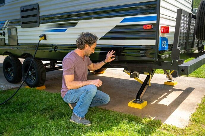 Man extending RV stabilizing jacks