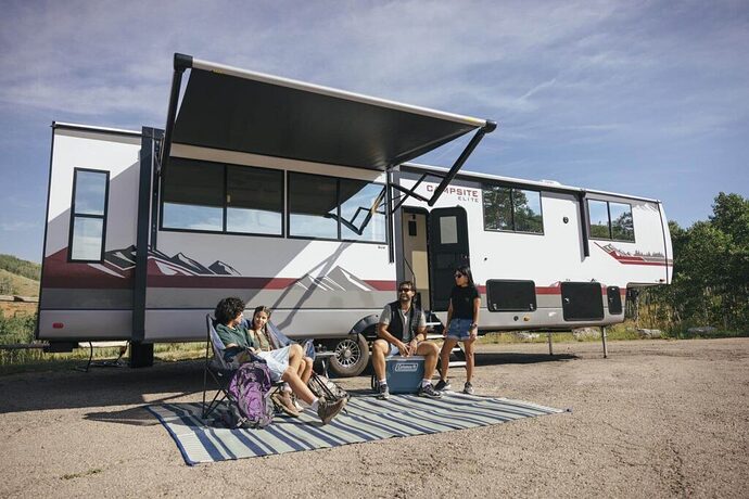 Family sitting under awning outside of Campsite Elite 5th wheel