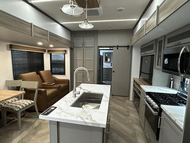 Sprinter 3900DBL interior showing kitchen with island, free-standing dinette and theater seating 