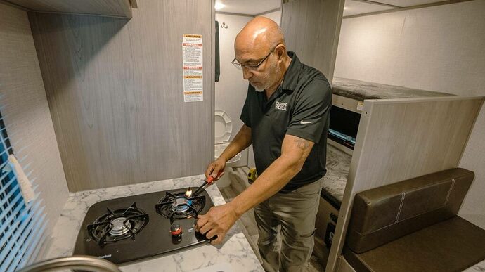 Man checking stovetop pilot light during RV shakedown trip
