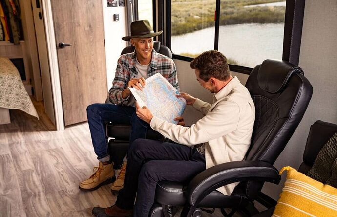 Men sitting in swivel chairs reading a map in toy hauler garage