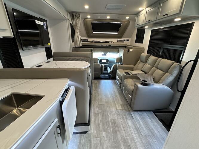 Interior image of the Dynamax Isata 6 31KS featuring the dinette and living area. The image faces the cab. 