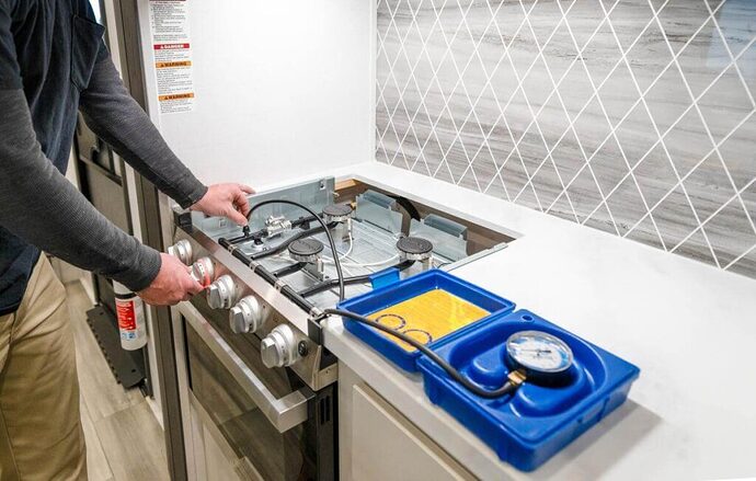 rv technician inspecting gas cooktop