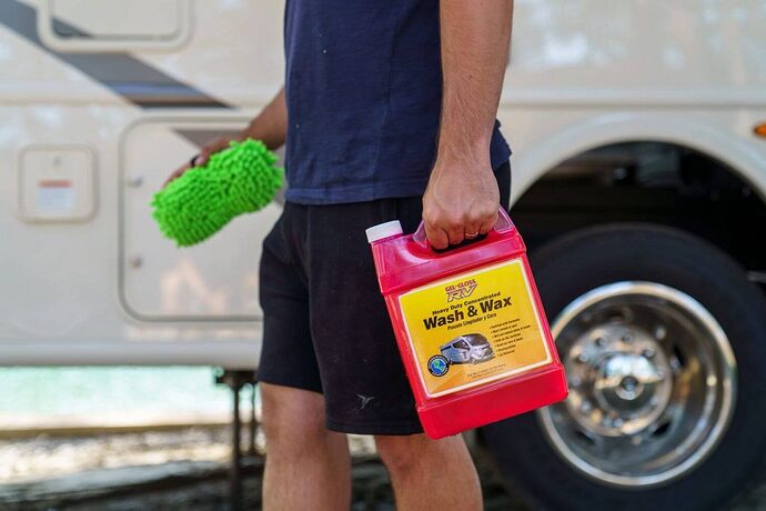 Man carrying RV wash and wax and a sponge