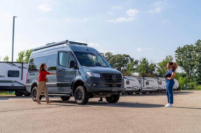 Couple talking to dealership staff when considering is now a good time to trade in an rv