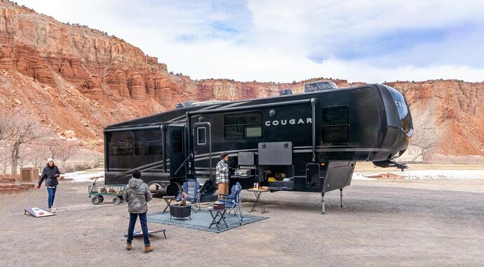 Family camping outside Keystone Cougar Midnight Edition fifth wheel