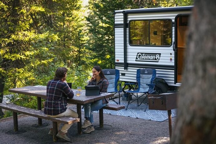 Couple at an RV campsite with woods in the background