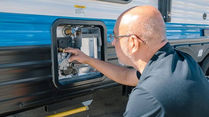 Technician prepping to drain camper water heater basic RV maintenance tips