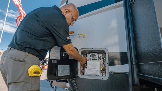 Technician performing preventive maintenance on RV water heater