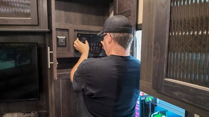 RV technician removing interior electrical panel