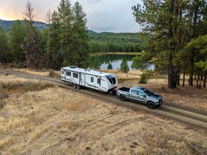 Truck towing long travel trailer by pond