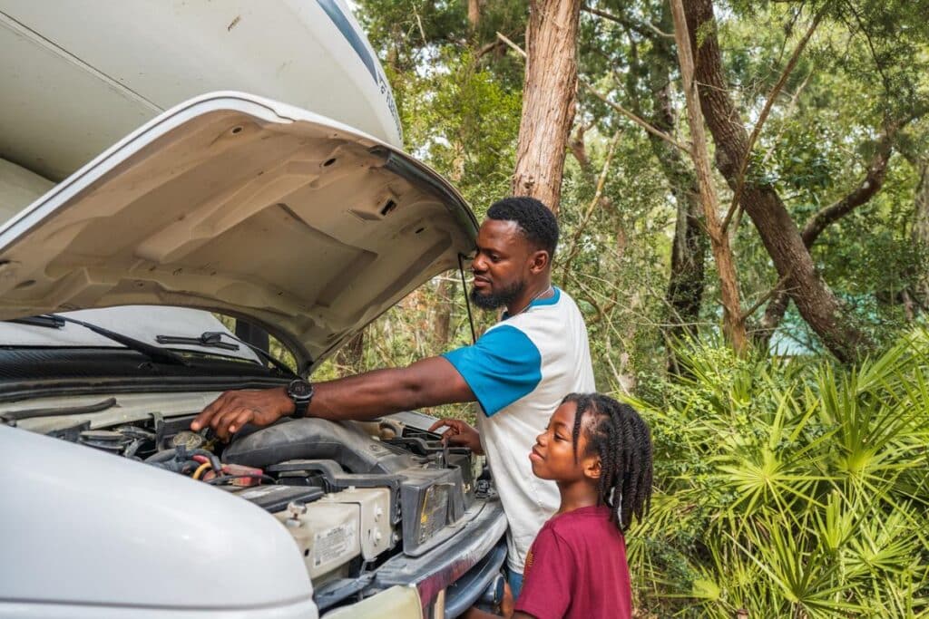 RV owner inspecting under the hood of a motorhome with an RV breakdown on the road