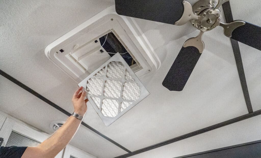 technician removing filter under interior RV AC cover